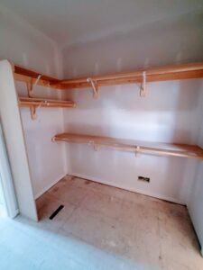 Closet shelving and hanging rods installed with raw wood and brackets, ready for paint.