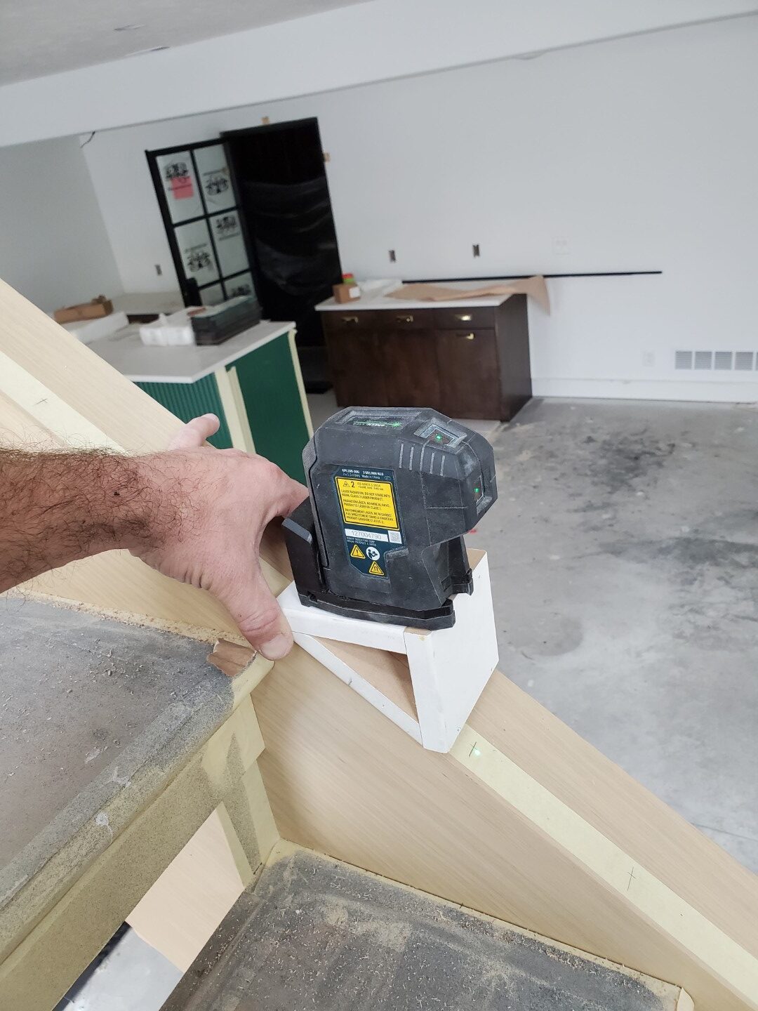 Laser level used for precise carpentry measurements during trim installation.