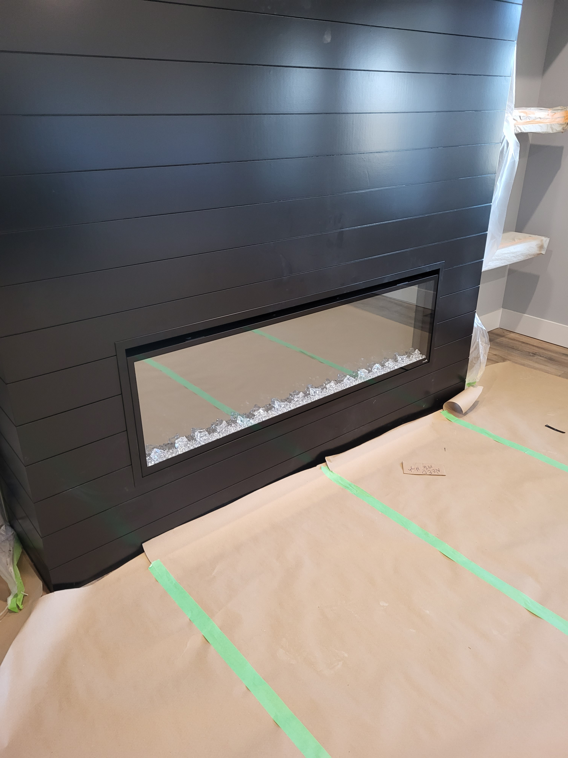 shiplap fireplace — modern black surround with glass front and decorative stones showing mitered corners