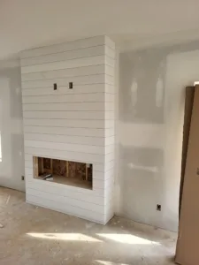 White shiplap fireplace chase with a corner return and firebox opening, room still at drywall stage
