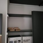 Multi-tier black shelving unit with finished wood frame and bullnose shelves installed in closet opening.
