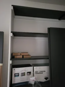 Dark finished bullnose shelves installed in closet with storage boxes stacked on the lower shelf.