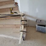 Stair skirt board clamped and fitted to staircase during trim installation—raw wood, pre-paint.