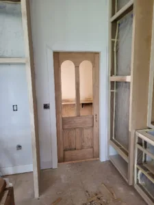 Wood door with arched glass lites, installed in a white cased opening.
