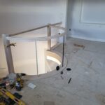 Curved wall framing and handrail installation in progress with drywall and metal studs visible.
