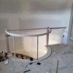 Curved handrail with newel posts and connectors installed during trim-out phase in curved architectural opening.
