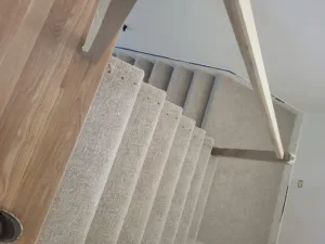 Finished stair treads with carpet runners and a white painted skirt board on a straight staircase.