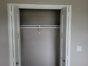 White closet doors opened wide, revealing an empty closet with a single hanging rod.