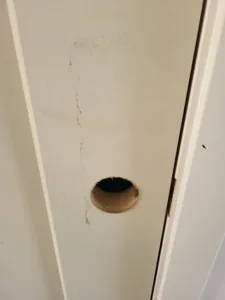 Incorrect: lockset bore hole in door edge with splintered, torn out wood around the rim