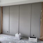Four-panel bypass doors installed and painted gray in closet opening with recessed pulls.