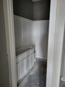 Painted white built in base cabinet with drawers in a narrow finished closet or hallway