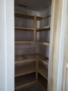 Corner closet shelving framed with raw wood cleats and multiple tiers, ready for finish