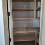 Custom built-in shelving unit with raw wood frame, multiple shelves, and vertical dividers ready for finishing.