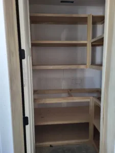 Corner closet shelving framed with raw wood cleats and multiple tiers, unfinished