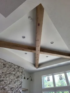 Unfinished wood ceiling beams crossing in an X pattern above a stone accent wall