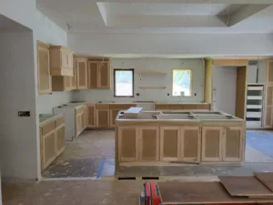 Kitchen cabinet installation with upper, lower, and island boxes in unfinished raw wood stage