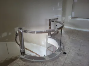 Curved handrail sections and fittings wrapped for protection around a stairwell opening.