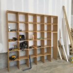 Custom built-in open shelving unit with wood frame and particle board shelves, installed in job site storage area.