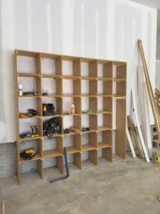 Open shelving unit with wood frame and particle board shelves, staged in a storage area