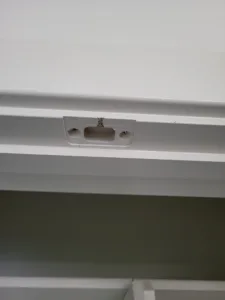 Routed keyhole slot with screw inside a white painted frame corner