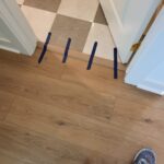 Painted interior doors installed with white finish, blue painter's tape marking floor transitions between rooms.