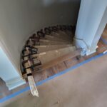Iron balusters set into stair treads with epoxy, fitted into handrail, completed curved staircase railing.