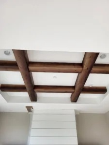 Dark stained ceiling beams crossing in a grid above a shiplap accent wall