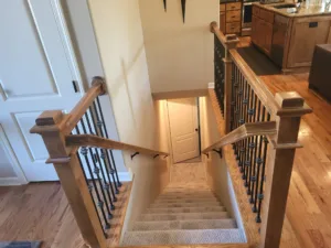 Overhead view of finished stairwell with wood newel posts, iron balusters, and wood flooring