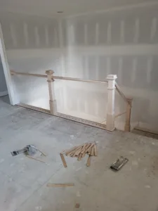 Raw wood newel posts and guardrail framing a stair opening, ready for paint