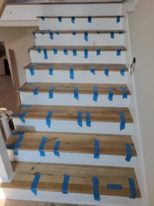 Finished interior staircase with wood treads and risers, taped for paint protection