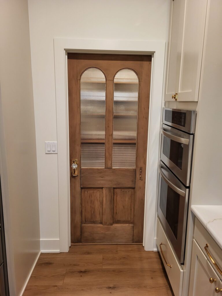 Custom wooden door with arched glass panels in a modern kitchen.