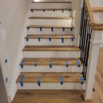 Stair treads installed and taped, risers painted, metal railing in place during construction phase.