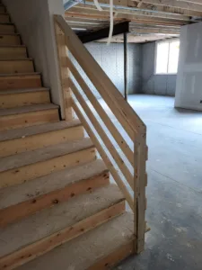 Horizontal wood slat railing with a raw wood post and treads, pre-paint stage