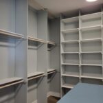 Finished face-frame closet shelving with painted white frame, multiple shelves, hanging rods, and vertical dividers installed.
