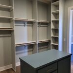 Painted closet shelving system with multiple rods, shelves, and vertical dividers installed in walk-in closet.