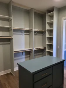 Multiple painted closet shelving bays with hanging rods and a dark drawer unit installed