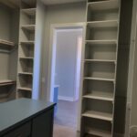 Painted face-frame closet shelving with multiple tiers and support brackets installed in walk-in closet.