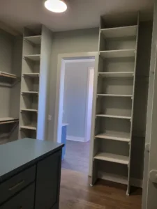Painted face frame closet shelving with tall vertical shelf towers flanking a walk-in closet entry.