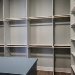 Walk-in closet with three tiers of shelving and hanging rods installed and painted white.