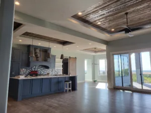 Finished kitchen and great room with painted cabinets, wood ceiling detail, and trim complete