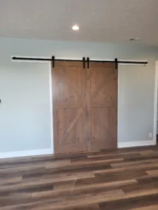 Stained wood barn door pair with X bracing closed together on overhead track hardware