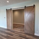 Pair of barn doors with X-bracing hung on black track hardware, flanking standard-height opening.