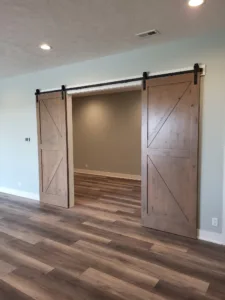 Barn door pair with X bracing hung open on black track hardware, flanking a doorway