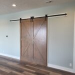 Pair of stained wood barn doors installed on overhead track with black hardware, standard 6'8" height.