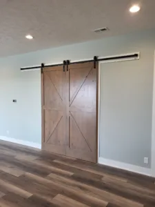 Stained wood barn door pair with X bracing hung on a black overhead track