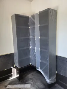 Installed cabinet boxes wrapped in plastic sheeting for protection during construction