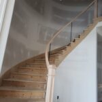 Curved staircase with finished wood treads, risers, handrail, and cable railing system pre-paint.