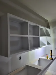 Open face wall shelving with multiple square compartments, white painted frame, mounted high on the wall