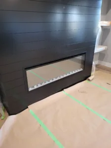 Dark horizontal shiplap wall treatment with integrated fireplace opening, fully painted.