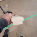 Primer application on concrete floor with painter's tape masking.